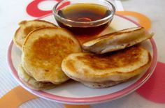 a plate topped with pancakes and syrup on top of a colorful tablecloth covered table