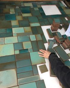 a person laying on the ground with their hands in front of some green and brown tiles