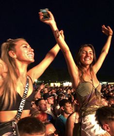 two beautiful women standing next to each other in front of a crowd