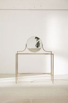 a mirror sitting on top of a table with a plant in the middle of it