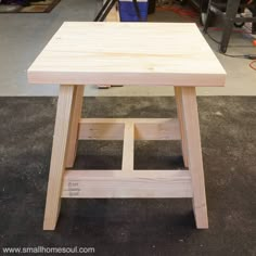 a small wooden table sitting on top of a hard wood floor in a room filled with tools