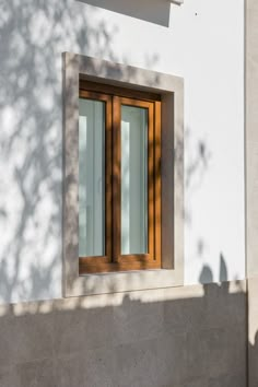 an open window on the side of a white building with wood trim and glass panes