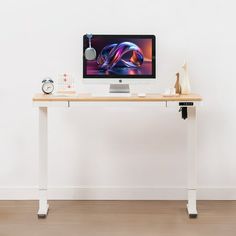 a computer monitor sitting on top of a wooden desk next to a clock and other items