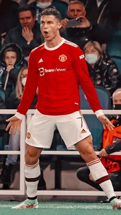 a man in red jersey standing on top of a soccer field with his mouth open