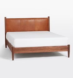 a wooden bed frame with white sheets and brown leather headboard on top of it