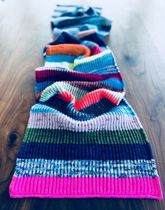 several knitted hats lined up on a wooden floor with one folded over the other