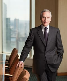 a man in a suit and tie standing next to a table with chairs on it