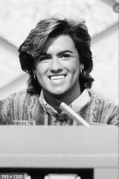 a black and white photo of a smiling man with a microphone in front of him