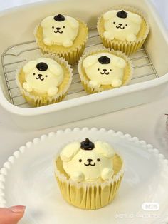 four cupcakes with frosting in the shape of dogs