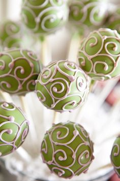 green and white cake pops with swirl designs on them in a clear glass bowl, ready to be eaten