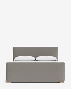 an upholstered bed with two pillows on the headboard and foot board in grey fabric