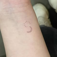 a small tattoo on the wrist of a woman's left arm that has a sun and moon