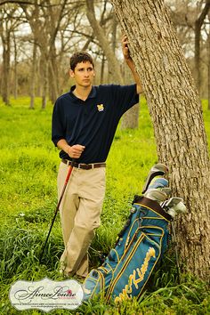 a man standing next to a tree with his golf bag