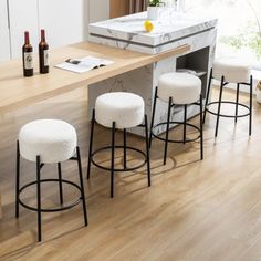 a kitchen island with four stools next to it and bottles on the counter top