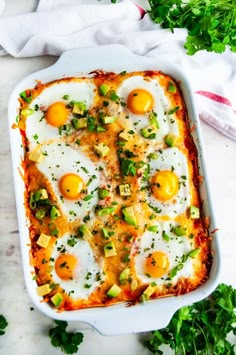 an egg enchilada in a white casserole dish with parsley on the side