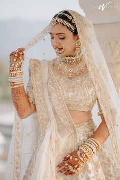 a woman in a bridal outfit with jewelry on her head and hands behind her back