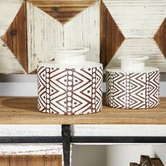 two white vases sitting on top of a wooden shelf