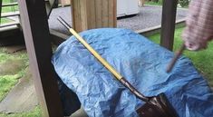 a blue tarp covering an umbrella on the back of a wooden bench in a yard