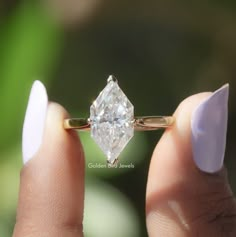 a woman's hand holding an engagement ring with a large diamond on the side