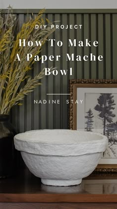 a white bowl sitting on top of a wooden table next to a vase and framed photograph