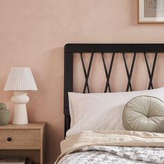 a bedroom with pink walls and a black headboard on the nightstand next to the bed