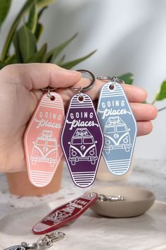 three keychains with the words going places printed on them are being held in front of a potted plant