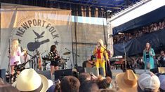 two women in cowboy hats are singing on stage with an audience behind them at a country music festival