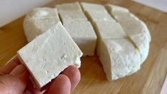 someone is holding some kind of cheese on a cutting board