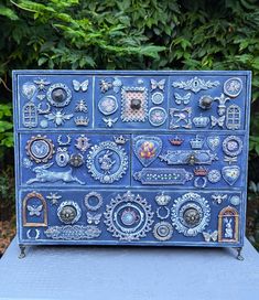 a blue painted dresser with lots of knobs and decorations on it's sides