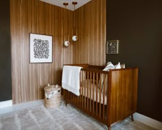 a baby crib in the corner of a room next to a wall with wood paneling