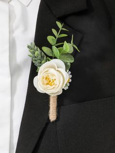 a boutonniere with white flowers and greenery on the lapel of a black suit