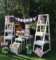 an outdoor party with white ladders and pink decorations on the grass, including cake