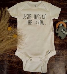 a baby bodysuit that says jesus loves me, this i know on the front