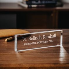 a clear acrylic plaque sitting on top of a wooden table next to a pen