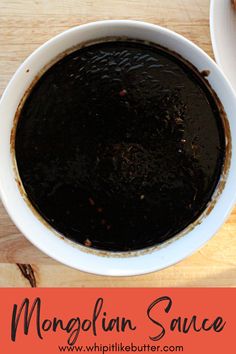 two bowls filled with black sauce on top of a wooden table