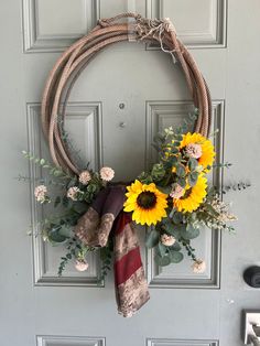 a wreath with sunflowers and greenery hangs on the front door