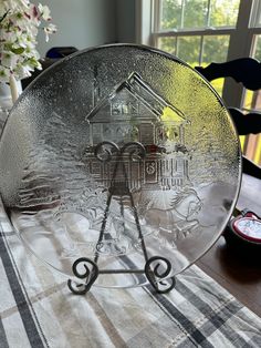 a glass plate sitting on top of a table next to a vase with flowers in it