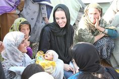 a group of women sitting around each other with a baby in their lap and smiling at the camera