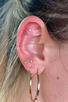 a close up of a person wearing gold hoop earrings with small stars on the inside of them