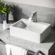 a white sink sitting on top of a counter next to a potted plant