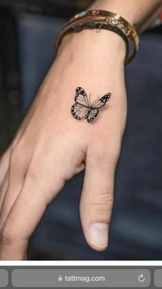 a woman's hand with a small butterfly tattoo on the middle finger and wrist