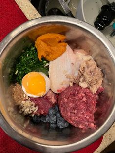 a metal bowl filled with meat, eggs and blueberries on top of a counter