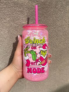 a hand holding a pink tumbler with the words grin on it and an image of santa