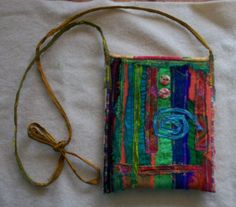 a multicolored purse with a string attached to it on a white cloth covered surface