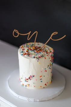 a white cake with sprinkles and the number one on it's top