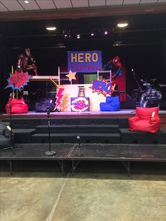 the stage is set up for an event with superhero themed decorations and props on it