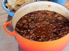 two bowls filled with chili and tortilla chips next to each other on a table