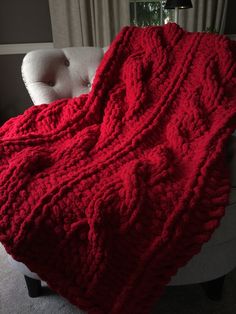 a red knitted blanket sitting on top of a white chair