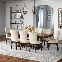 a dining room table and chairs with white upholstered chairs on top of a rug