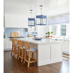 a kitchen with white cabinets and blue pendant lights hanging from the ceiling over the island